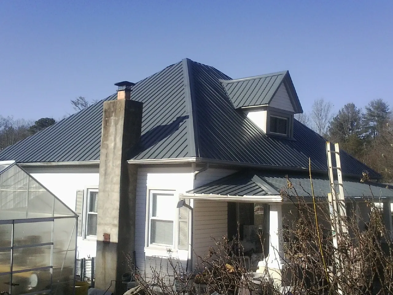 Dark blue standing seam metal roof on a white farmhouse with dormer — Slate & Tile Roof Repair by Roofing Brothers in Susquehanna