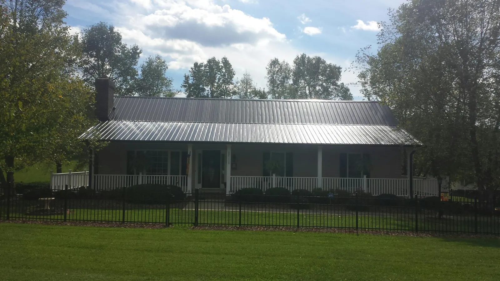 Gray metal roof on a brick ranch with a full width front porch — Gutter Guard Installation work by our crew in Susquehanna