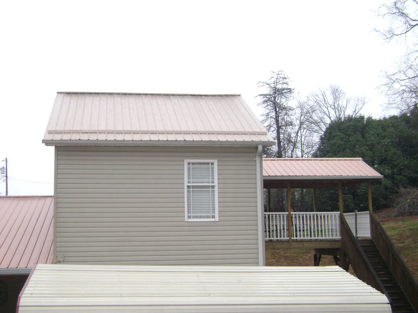 Tan metal roofs on a two story addition and attached porch, from a Roof Replacement job in Susquehanna