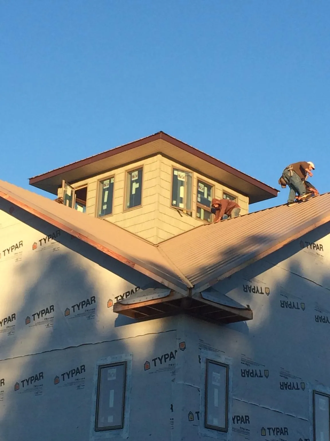 Roofers working around a rooftop cupola on a new metal roof at sunset — Roof Waterproofing in Susquehanna by Roofing Brothers